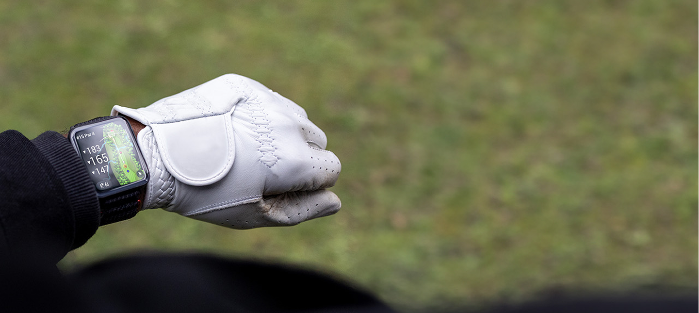 Hand wearing a white golf glove with a blurred green background